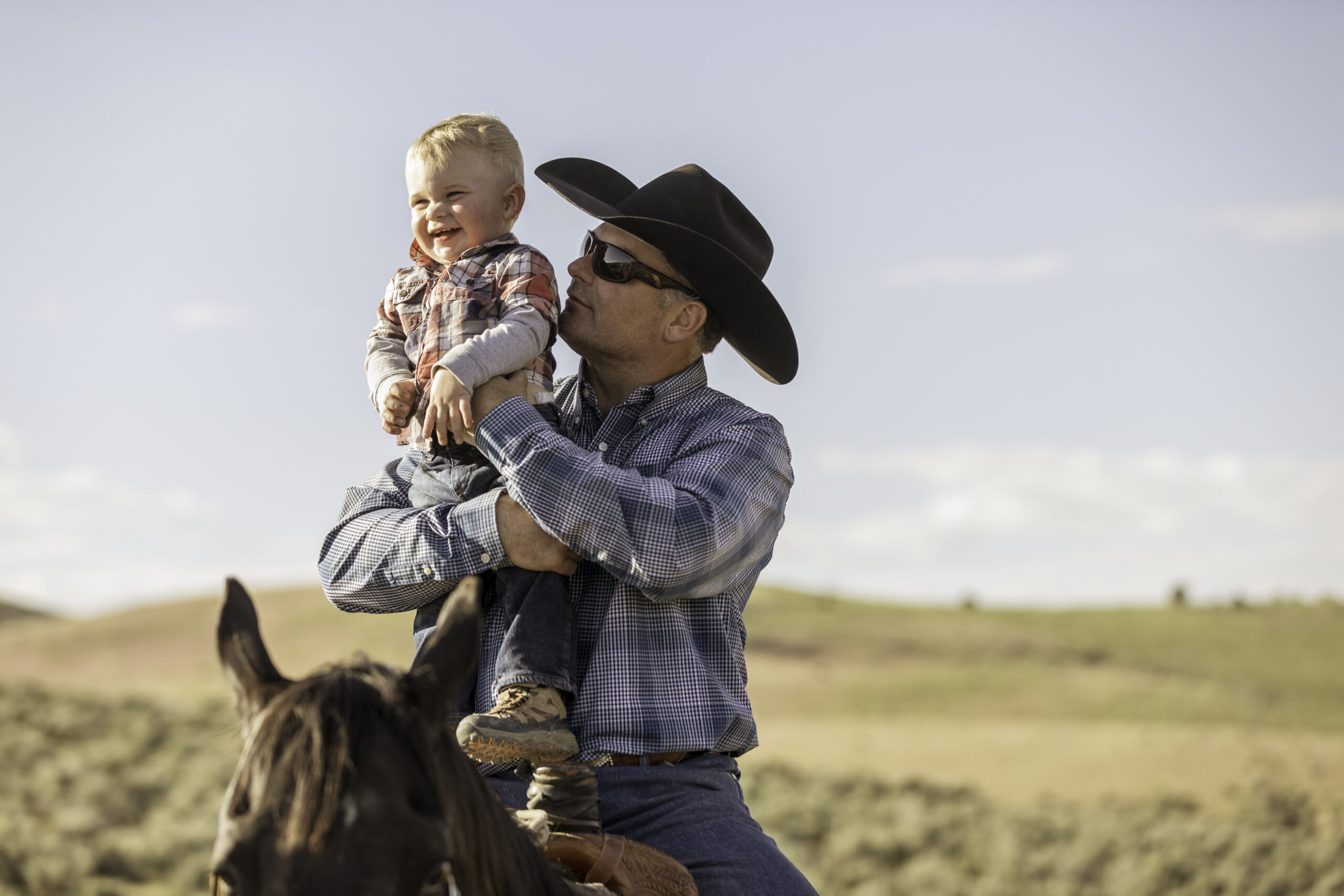 Stock photo of a father and son on horseback in the Utah countryside.
