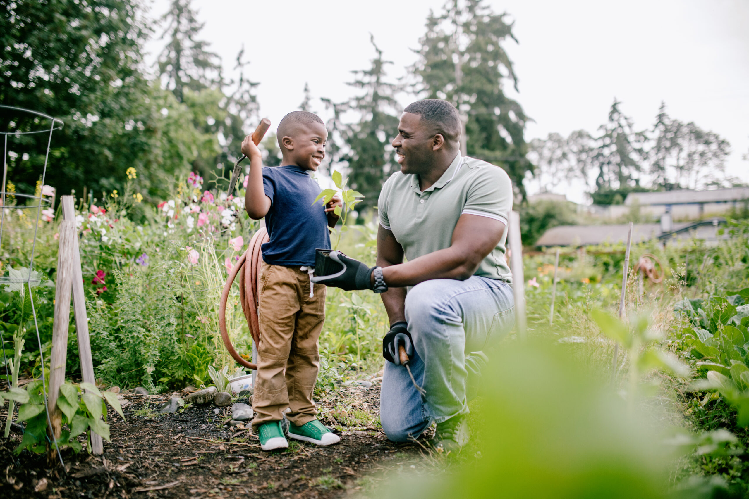 An African American father teaches his son about caring for the earth in a community vegetable garden. A time of relationship building and education.